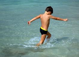 Child Boy walking away through water