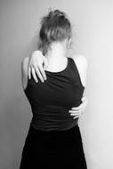 girl in a black T-shirt hugs herself behind her back, monochrome