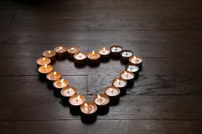 Beautiful and colorful heart, made pf the candles, on the wooden surface, in light