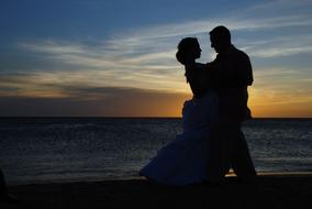 Couple together on the beautiful Caribbean beach at colorful sunrise, on wedding