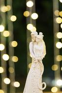 Beautiful cake figure of the groom and bridge, at background with colorful bokeh lights