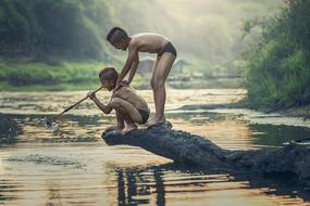 Boys, fishing near the water, among the plants in Cambodia, with a spear