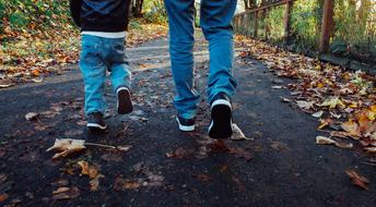 Dad and son are walking along the path in the autumn park