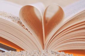 Book with Heart shaped pages on sand close-up