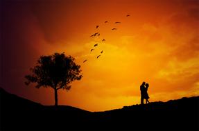 Couple Kissing on hill slope at sunset