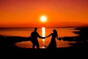 newlyweds by the sea on a background of orange sunset