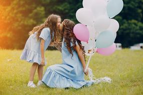 mom with balloons kisses daughter