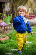 happy child in a blue jacket and yellow pants