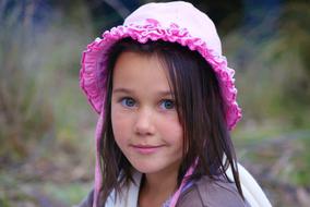 Portrait of the smiling child girl in pink, decorated hat