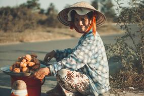 elderly asian woman sells food at road close-up on blurred background