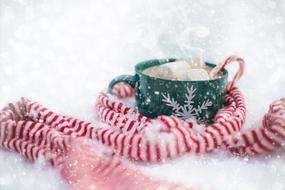 cup of hot chocolate and a striped scarf under the snow