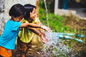 children play under running water