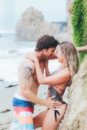 happy Couple, young Boy and Girl kissing at rock on beach