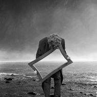 monochrome photo of a lonely man with a mirror on the seashore