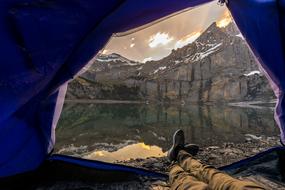 male legs stretched from tent at scenic mountain landscape on the coast, Adventure, Concept