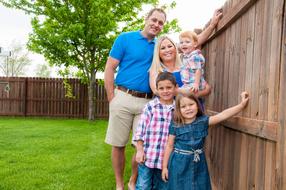 photo of a family on the background of a fence in the garden