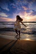 long hair Girl walks on beach at sunset