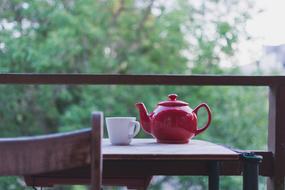 Red teapot and white cup on the wooden table