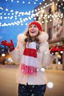happy young girl in winter clothing looking at Christmas Lights in city