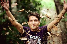man throwing autumn leaves