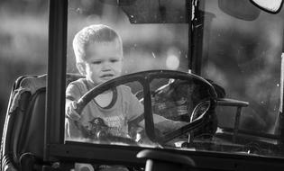 black and white photo of a boy driving a tractor