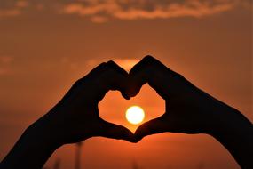 orange setting sun in heart hand