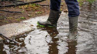 a boy in rubber boots is standing in a puddle