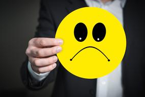 sad emoji sign in man's hand
