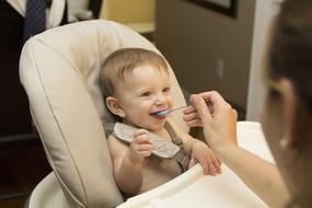 mother feeds the child in the high chair