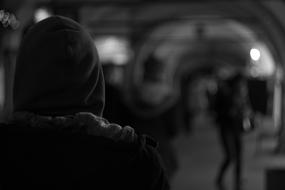 black and white photo of a man in a hood in the subway