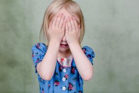 Child closes her eyes with her hands