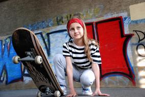 photo of a girl in a striped t-shirt with a skateboard