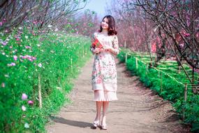 photo of an asian girl in a spring dress on a background of a blooming garden