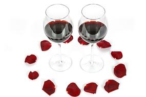 two glasses of red wine and rose petals on the table