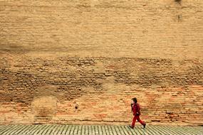 running child near a high brick wall