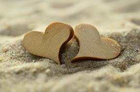 two wooden hearts lie on the sand on the beach