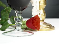 a glass of red wine, a candle and a red rose