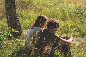 young boy and girl sitting on grass at summer