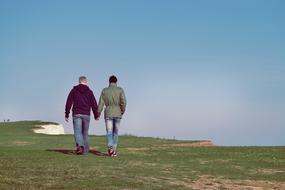 couple holding hands and walking at the top of the cliff