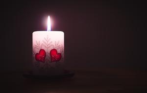 burning Candle with two painted hearts at darkness