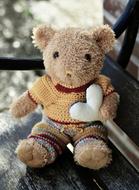 teddy bear with a white heart on a bench