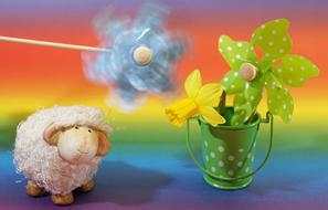 paper flowers and wooden sheep on a rainbow background