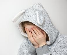 Desperate child girl closing face with hands