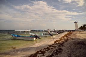 fishing boats stand on the shore against the backdrop of a lighthouse in Mexico