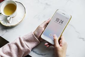 smartphone in female hands and vintage cup with drink on table