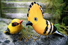 two yellow wood birds on a stone