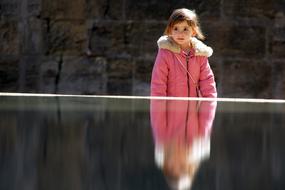 child Girl in pink jacket at water