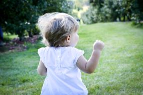 Child girl in white dress Runs away in park