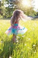 girl in a beautiful dress is dancing in the meadow