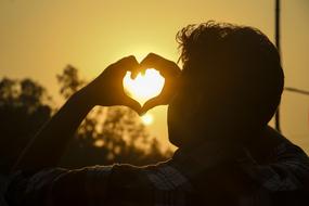 a man by the window makes a heart out of his hands